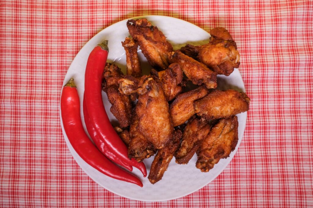 chili peppers and fried chicken wings on plate on table