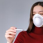 woman in face mask checking thermometer