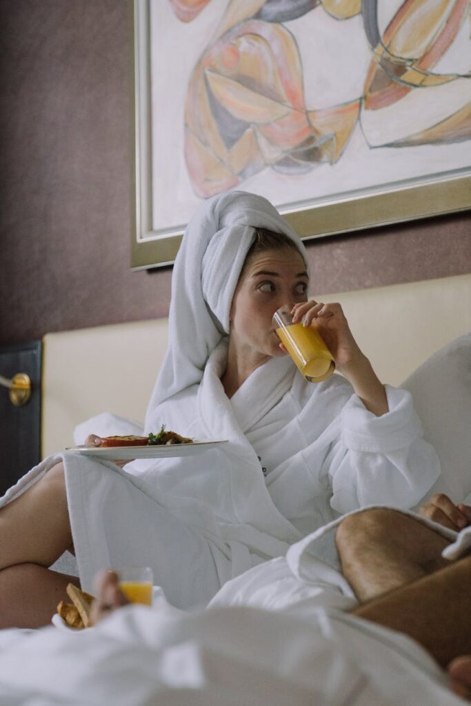 woman in bathrobe drinking orange juice