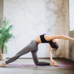 woman in gray leggings and black sports bra doing yoga on yoga mat